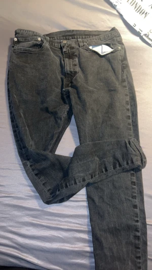 Levi's 511 svarta jeans - Svarta Levi's 511 jeans med klassisk femficksdesign och smal passform. Jeansen har en snygg mörk tvätt och är tillverkade i slitstarkt denim. Märkespatch i svart läder baktill och röd Levi's-tag på bakfickan. Perfekta för en cool och avslappnad stil.