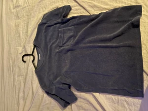 Blå kort klänning från KappAhl - En enkel blå kort klänning från KappAhl med rund halsringning, korta ärmar och en bröstficka. Mjuk och skön, perfekt för en avslappnad stil. Passformen är normal och materialet känns som bomull.