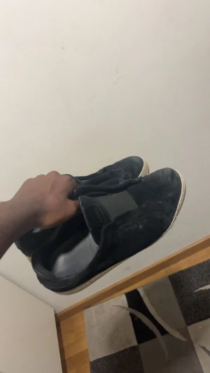 Svarta slip-on sneakers mocka - Svarta slip-on sneakers från arigato med vit platt sula och elastiska paneler på ovansidan för enkel påtagning. Skorna är gjorda i mocka och har en stilren, rund tå. Perfekt för dig som gillar enkel och clean streetstil.