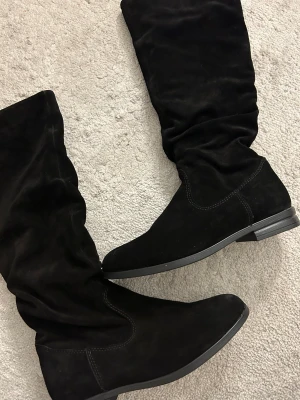 Svarta boots 37 - Säljer dessa svarta skor köpt på about you, aldrig använda! Nypris 995kr. Mocka imitation och går upp till precis under knäna!