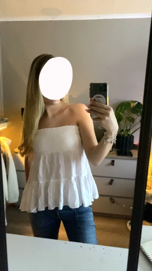 Vit bandeau tubtopp med volang - Säljer en vit bandeau tubtopp med smock upptill och bred volang nedtill. Toppen är axelbandslös och har en luftig, flowy passform 🤍 aldrig använd 