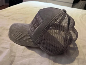 Grå Leksands IF keps med autografer från alla förra årets spelare använd en gång - Säljer en grå keps från Leksands IF med mesh på sidorna och böjd skärm. Framsidan har ett stort broderat märke med klubbens namn och motiv. Kepsen är signerad med flera autografer på undersidan av skärmen. Perfekt för dig som älskar hockey och vill sticka ut.