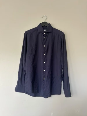 Mörkblå skjorta från Eton i merinoull - Snygg mörkblå skjorta från Eton i slim fit med klassisk krage och vita knappar. Tillverkad i mjuk merinoull som känns lyxig mot huden. Långärmad modell med stilrena manschetter, perfekt för dig som gillar en clean och modern look.