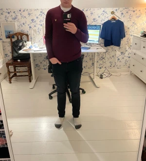 Grish Vinröd tröja från Lyle & Scott - Säljer en vinröd tröja från Lyle & Scott med deras ikoniska gula logga på bröstet. Tröjan har långa ärmar och ribbade muddar vid ärmslut och nederkant. Perfekt för en stilren look. Tröjan har även ett litet hål vid halskragen, Hålet syns inte när man har på sig tröjan 