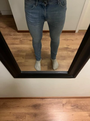 Ljusblå tiger of Sweden slim fit jeans - Säljer ett par ljusblå slim fit jeans med klassisk femficksdesign och normal midja. Jeansen har en snygg tvätt och sitter tight hela vägen ner. Perfekta för dig som gillar en modern och stilren look.