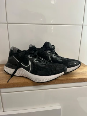 Nike svartvita sneakers - Säljer ett par svarta Nike sneakers med vit sula och vit swoosh-logga på sidan. Ovandelen är i meshmaterial för bra andningsförmåga och skorna har klassisk snörning. Perfekta för dig som gillar sportig och stilren look.