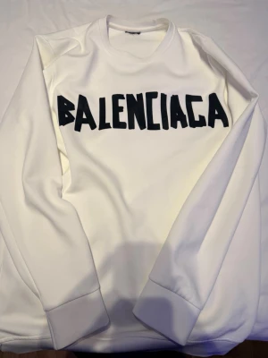 Vit sweatshirt  - Vit sweatshirt  med stor svart logotyp på bröstet. Tröjan har rund halsringning och långa ärmar. Tillverkad i mjukt material som känns skönt mot huden. Perfekt för dig som gillar streetwear och vill sticka ut.