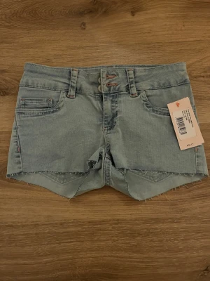 Ljusblå jeansshorts -  ljusblå jeansshorts från Nelly med broderade detaljer med rosa och blått på bakfickorna. Lappen är kvar