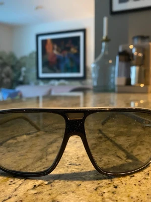 Svarta pilotbågar solglasögon - De som syns är bara damm på efter dem har stått ett tag, inget allvarligt smutts. Köpta secondhand på Herr Judit. Svarta pilotbågar och mörka linser. Klassisk aviator-stil med bred ram och dubbla näsbryggor. Perfekta för dig som vill ha en cool och tidlös look. Passar till de flesta outfits och ger en edgy vibe. 