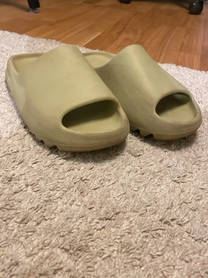 Yeezy slides - Tjena, säljer nu mina Yeezy slides då dem har blivit för små. Storleken är 46 men dem är ganska små i storlek så passar 43-44,5 skulle jag säga. Dem är otroligt bekväma och passar bra till sommaren, samt passar till många outfits. Box finns ej tyvärr men självklart är den äkta. Skriv för minsta fråga!