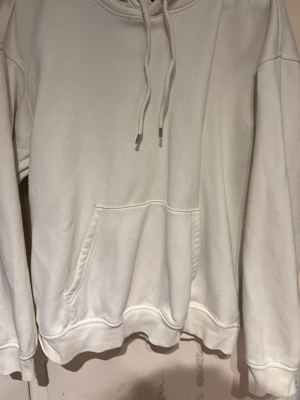 Vit hoodie från H&M Loose Fit - Säljer en vit hoodie från H&M i loose fit-modell. Hoodien har huva med dragsko, stor magficka och ribbade muddar vid ärmslut och nederkant. Tillverkad i mjukt bomullsmaterial som är skönt att bära. Perfekt för en avslappnad och stilren look. Använd fåtal gånger men dock börjat få noppror.