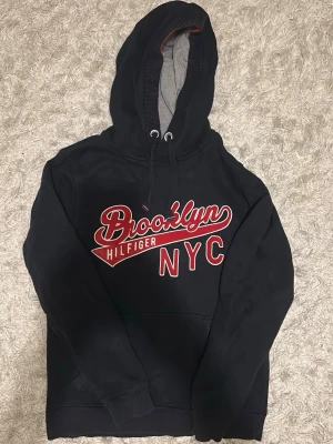 Mörkblå hilfiger hoodie - Mörkblå hilfiger hoodie med tryck och snören, storlek M, bra skick utan defekter. Hör gärna av dig vid fråga.