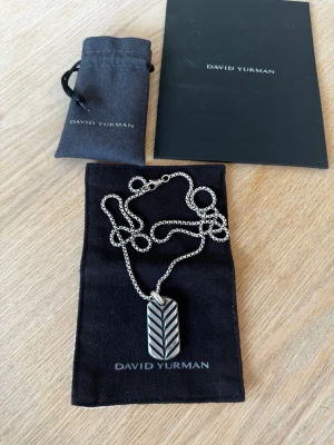 David Yurman halsband med Streamline Tag - Snyggt halsband från David Yurman. Kedjan är deras klassiska box chain i silver 2,7mm & 26 inch (66cm). Tagen är deras Streamline tag 35mm. Kommer med originalpåse och förvaringspåse. Nypris 775€ för båda två. 