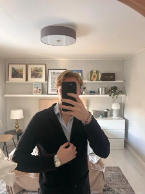 Mörkblå stickad Massimo dutti kavaj - Stilren mörkblå kavaj med två knappar framtill och klassiska slag. Kavajen har två fickor och är tillverkad i ett mjukt tyg som ger en avslappnad men ändå dressad look. Perfekt att matcha med skjorta för en snygg outfit.