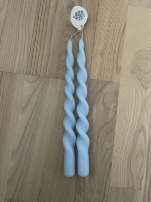 Två ljusblå spiralformade ljus - Säljer två snygga ljusblå stearinljus med spiralformad design. Perfekta som dekoration eller för mysiga kvällar. Ljusen är oöppnade och sitter ihop med en etikett.