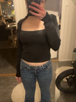 Svart croppad topp med lång ärm - Trendig svart croppad topp med lång ärm och fyrkantig urringning. Sitter tight och har en stilren look som passar till mycket. Perfekt att matcha med jeans eller kjol för en cool outfit.