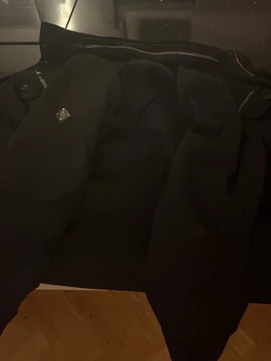 Svart jacka från j lindeberg - Snygg svart pufferjacka från j lindeberg med quiltad design och dragkedja framtill. Jackan har en klassisk pufferlook och en liten logodetalj på ärmen. Perfekt för kyliga dagar och enkel att matcha med allt. Riktigt grich