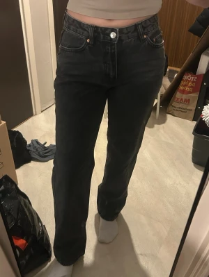 Zara Midrise Jeans  - Säljer ett par svarta jeans med raka ben. Jeansen har klassisk femficksdesign och stängs med knapp och dragkedja. Perfekta för en avslappnad och trendig look.