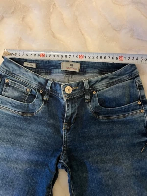 LTB jeans Valerie - Snygga blå jeans från LTB, modell Valerie. Klassisk femficksdesign med dragkedja och knapp framtill. Jeansen har en tvättad look med lätt slitningar. Perfekta till vardagsstilen och passar till det mesta.