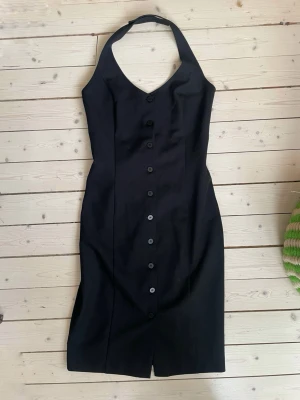 Klänning med halterneck  - Figursydd halterneckklänning med knappar framtill. Snygg att ha antingen som den är eller med vit skjorta under. Strl S men mer som XS i storlek. Mycket fint skick!   ✨ Se även mina andra annonser, 3 för 2 på allt! ✨