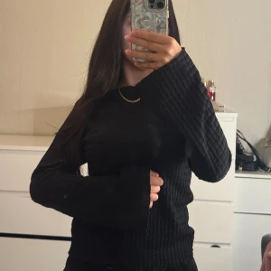 Svart stickad tröja med vida ärmar - Säljer en svart stickad tröja med snyggt strukturerat mönster och vida långärmar. Aldrig använd 