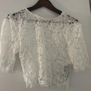 Vit spetsblus från Amisu XS - Säljer en vit blus från Amisu i storlek XS. Blusen är helt i spets och har trekvartsärmar. Den är lätt transparent och har fransiga kanter vid ärmslut och nederkant. 