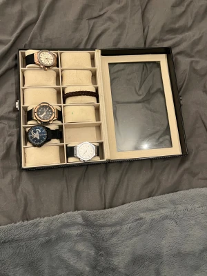 Klocklåda+4 klockor och ett armband - Säljer ett klockset med fyra olika herrklockor i svart, silver och guldtoner. Lådans glas har en spricka och ingen av klockarna funkar(man behöver byta ut batteriet bara).