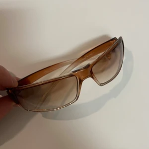 Valentino Solglasögon - BUTIKSPRIS 2500kr. Snygga solglasögon från VALENTINO OLIVER med brun transparent båge och rektangulära linser i en tonad brun färg. Glasögonen har en sportig och modern design, tillverkade i Italien. Perfekt accessoar för soliga dagar. PRISET KAN DISKUTERAS.
