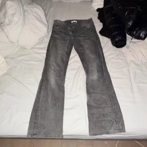 Grå bootcut jeans - Säljer ett par grå jeans med bootcut passform. Byxorna har klassisk femficksdesign och är tillverkade i jeansmaterial. Perfekt för dig som gillar en lite vidare siluett nedtill och vill ha en cool, avslappnad look.