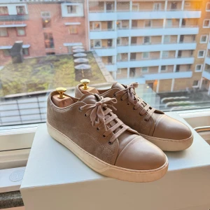 Lanvin sneakers  - Lanvin toe cap sneaker i beige mocka med nappa läder på tån. Väldigt fint skick och inga fläckar eller liknande bortsett från sulan. Box, dustbag, kvitto och nya skosnören medföljer. Storlek 7 - sitter som 42. OBS Skobloxk ingår ej