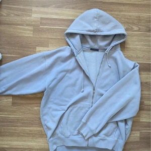 Ljusblå hoodie från Brandy Melville - Mysig ljusblå hoodie från Brandy Melville med dragkedja, huva och snörning. Tröjan har fickor framtill och är fodrad med mjuk fleece på insidan. Perfekt för chill dagar och har en oversized passform.