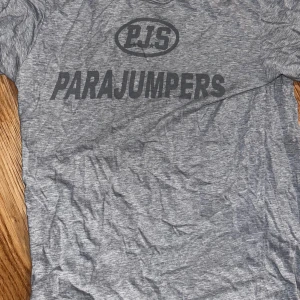 Grå t-shirt från Parajumpers - Snygg grå t-shirt från Parajumpers med stort tryck på bröstet. Klassisk rund hals och korta ärmar. Mjuk och skön bomullskvalitet som passar perfekt till jeans eller shorts. Logotypen PJS syns tydligt framtill för en cool look.   Inga fel , köpt från Johnells för ett tag sen ord pris 1299kr Behöver bara strykas 
