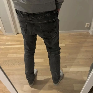 Replay Anbass  - Säljer ett par svarta stilrena Replay jeans med lite snygga slitningar. Jeansen sitter slim fit med normal midja och raka ben. Modellen på bilden är 180 och väger 63 kg. Tvekan inte på att höra av dig vid fler frågor! 