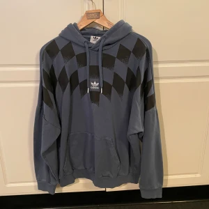 Blå Adidas hoodie med svarta chackrutor - Säljer denna blåa Adidas hoodie med svarta chackrutor i storlek M. Den är i en oversized fit så den sitter mer som kanske L eller XL men det beror ju såklart på hur man vill att den ska sitta. Hoodie inhandlades vintern 2023 och säljs inte längre men nypris låg då på 900kr. Tröjan har använts sparsamt och är därför i nästintill nyskick. Hör av er vid eventuella funderingar!