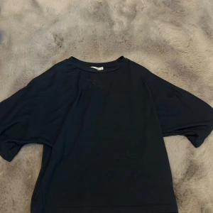 Mörkblå loose t-shirt från Lager 157 - En mörk blå t-shirt från Lager 157 med loose passform och korta ärmar. Enkel och stilren design med rund halsringning, perfekt för dig som gillar en chill och avslappnad look. Materialet är mjuk bomull som känns skönt mot huden.