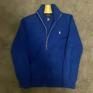 Blå stickad kofta från Polo Ralph Lauren - Riktigt snygg blå stickad kofta från Polo Ralph Lauren med dragkedja och ribbade muddar. Tröjan är i nästan nyskick och har inga som helst defekter‼️ Storlek 14-16 som motsvarar 160 , passar perfekt på någon runt 165. Hör av dig direkt vid frågor eller funderingar!😁
