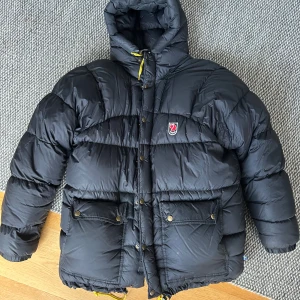 Svart dunjacka från Fjällräven XS - Svart pufferjacka från Fjällräven i storlek XS. Använd ett fåtal gånger men säljer då den är för stor. Strl XS men funkar absolut som en större storlek, ca M. Väldigt bra skick. Köpte den här på Plick föra året, men påse finns med. Stor i storleken. 