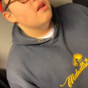 Blå hoodie med gul Midnattsol-tryck - Säljer en blå hoodie med gul text och sol-tryck på bröstet där det står 'Midnattsol'. Tröjan har huva med metallöljetter och en avslappnad passform. Perfekt för dig som gillar streetwear och vill sticka ut med en unik print.