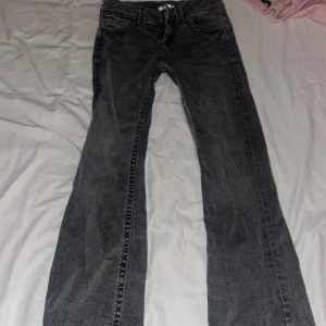 Svarta jeans från Gina Tricot, stl 158 - Säljer ett par ljus gråa jeans från Gina Tricot i storlek 158. Jeansen har klassisk femficksdesign, raka ben och snygga slitningar för en cool look. Materialet är jeans och de har knappar framtill. Perfekt för dig som gillar en avslappnad stil. Dom är ljusare i verkligen geten