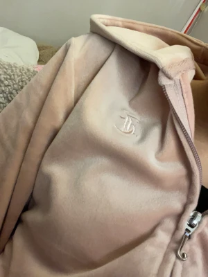 Ljusrosa velour hoodie Juicy Couture - Säljer en ljusrosa hoodie från Juicy Couture med dragkedja och huva. Tröjan är i mjuk velour med broderad JC-logga på bröstet och har två fickor.