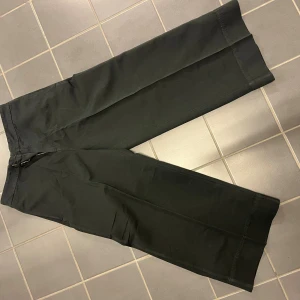 Svarta wide Flame Trousers från Hope - Säljer ett par svarta Flame Trousers från Hope i storlek 40. Byxorna har breda ben, raka fickor bak och stängs med dragkedja och knapp. Materialet är en mix av bomull, linne och lyocell som ger en skön känsla och snygg struktur.