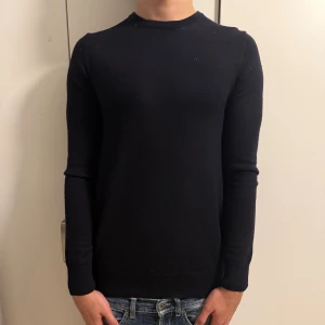 Mörkblå merinoull tröja från J.Lindeberg - Mörkblåstickad tröja från J.Lindeberg i storlek M. Tröjan har en klassisk rund hals och långärmade smala ärmar. Materialet är merinoull, storlek M men passar som S också,nyskick, nypris-1300 mitt pris-500