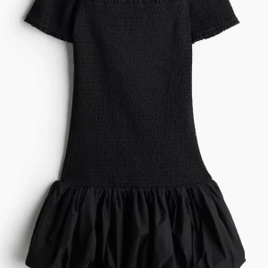 Svart kort klänning med volang - Populära klänningen från HM! Supersnygg svart kort klänning med offshoulder och volang nertill. Smockad överdel som sitter tight och ger en cool siluett. 
