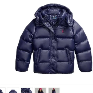 Mörkblå pufferjacka från Polo Ralph Lauren - Säljer min mörkblå pufferjacka från Polo Ralph Lauren med röd logga på bröstet. Jackan har huva, dragkedja och knappar framtill, samt två stora fickor. Den är dunfylld och i storlek 164-176 vilket motsvarar xs