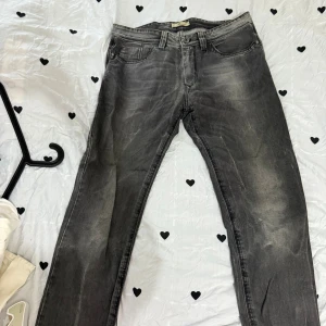 Grå jeansbyxor med straight fit - Snygga grå jeansbyxor med klassisk femficksdesign och raka ben. Jeansen har en cool tvättad look och knappar i midjan. Perfekt för dig som gillar en enkel och stilren vibe till vardags. Passar till sneakers eller boots.