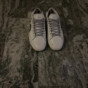 Oliver Cabell vita sneakers strl 44 - Snygga vita sneakers från Oliver Cabell med grå snörning och svart mockadetalj på hälen. Skorna har en rund tå och platt sula, samt en svart cirkeldetalj på sidan. Designade i Italien och tillverkade i Vietnam. Perfekt för dig som gillar stilrena och moderna sneakers. KVITTO FINNS!    HÖR AV DIG VI FRÅGOR!