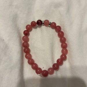 Rosa pärlarmband med silverdetaljer - Snyggt armband med runda rosa pärlor och små silverfärgade detaljer. Elastiskt band gör det enkelt att ta på och av. Perfekt accessoar för att ge din outfit en färgklick och lite extra stil.