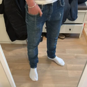Blå slim fit jeans från J.lindeberg  - Säljer ett par blå J.lindeberg jeans i slim fit-modell med klassisk femficksdesign. Jeansen har en snygg tvätt med lätt slitning och raka ben. Perfekta för dig som gillar en stilren och enkel look. Materialet är mjukt och följsamt jeans.