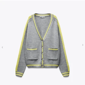 Grå kofta med gula ränder från Zara - Snygg grå kofta från Zara med gula och ljusgrå ränder längs kanterna och ärmarna. Koftan har två fickor framtill, v-ringad hals och knappar. Perfekt för dig som gillar en chill och färgglad stil.