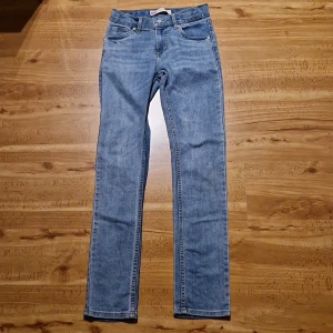 Levis 510 jeans - Säljer ett par Levi's 510 Skinny jeans i ljusblå denim i storlek 14A/164. Klassisk femficksmodell med smal passform och raka ben. Jeansen har snygga kontrastsömmar och Levi's ikoniska läderpatch bak i midjan. Perfekta för dig som gillar en modern och clean look.